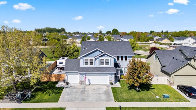 view of front of house with driveway, a residential view, fence, a front lawn, and an attached garage