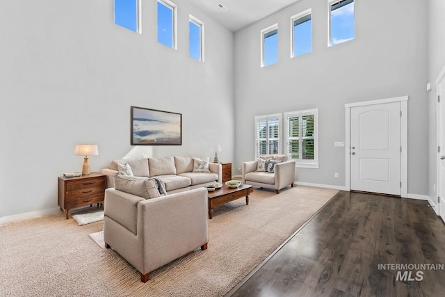 living room with a healthy amount of sunlight, baseboards, and a towering ceiling