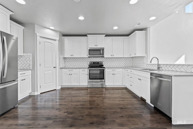 kitchen with appliances with stainless steel finishes, tasteful backsplash, a sink, white cabinets, and recessed lighting