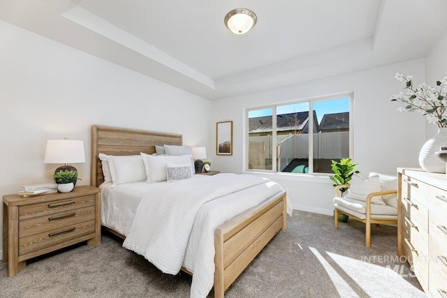 carpeted bedroom with a raised ceiling