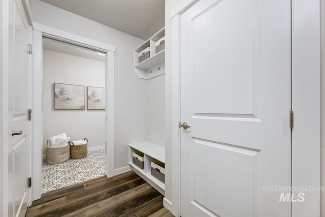 mudroom with a textured ceiling, baseboards, and dark wood-style floors
