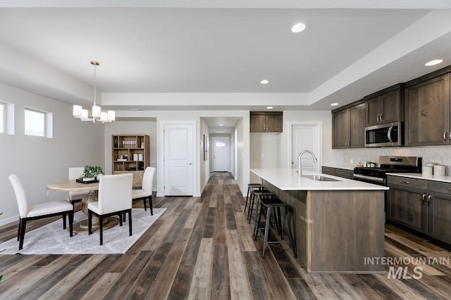 kitchen featuring a sink, appliances with stainless steel finishes, light countertops, and dark brown cabinets