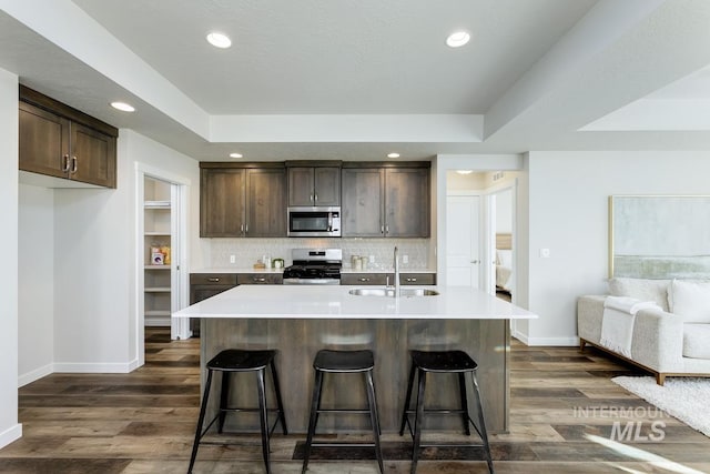 kitchen with a sink, baseboards, stainless steel appliances, and dark brown cabinets