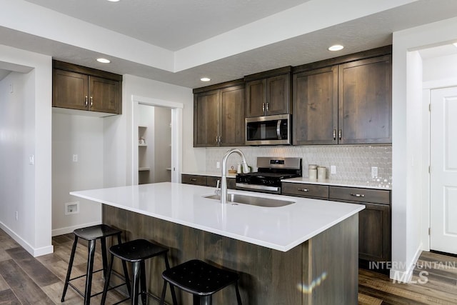 kitchen with a sink, baseboards, dark brown cabinetry, and stainless steel appliances
