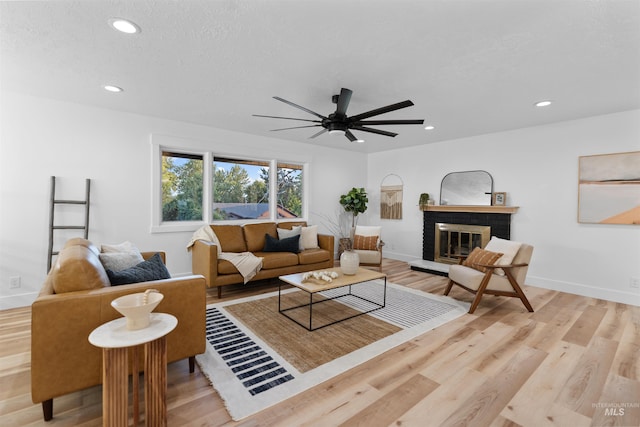 living area featuring a brick fireplace, baseboards, wood finished floors, and recessed lighting