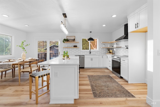 kitchen with a sink, stainless steel appliances, wall chimney exhaust hood, and open shelves