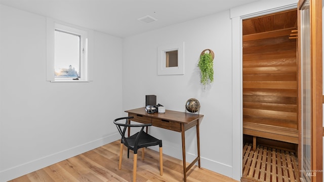 office area featuring light wood-type flooring, a sauna, visible vents, and baseboards