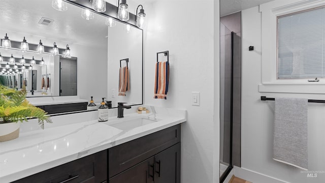 bathroom with a textured ceiling, a stall shower, vanity, and visible vents