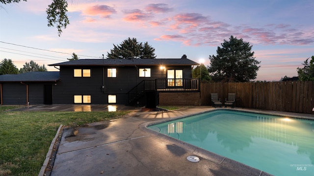 pool at dusk with a fenced in pool, stairway, fence, a yard, and a patio area