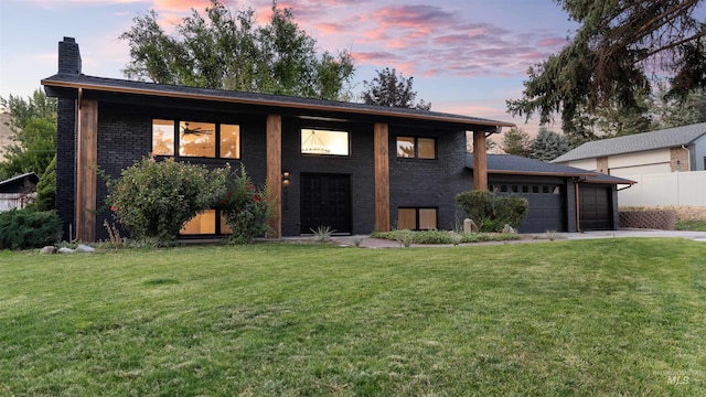 view of front of house with driveway, a chimney, an attached garage, a front lawn, and brick siding