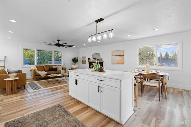 kitchen with recessed lighting, light wood-style flooring, white cabinetry, and decorative light fixtures