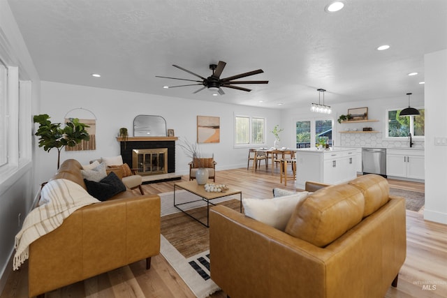 living room with recessed lighting, a brick fireplace, and light wood-style flooring