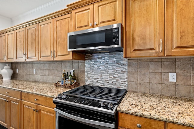 kitchen featuring tasteful backsplash, crown molding, light stone countertops, and stainless steel appliances