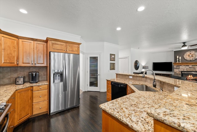 kitchen featuring ceiling fan, sink, light stone countertops, black dishwasher, and stainless steel fridge