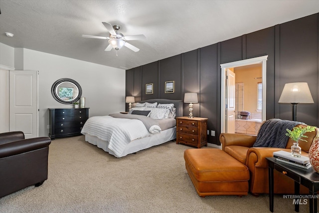 carpeted bedroom with a textured ceiling, connected bathroom, and ceiling fan