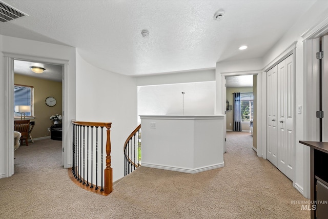 corridor featuring light carpet and a textured ceiling