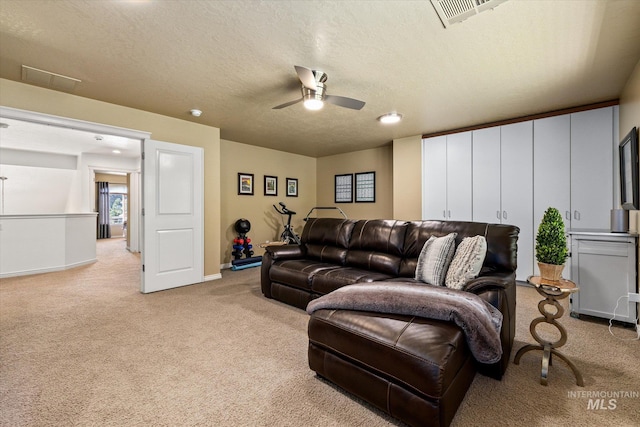 carpeted living room featuring ceiling fan and a textured ceiling