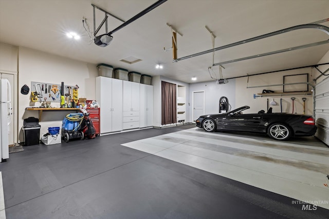 garage featuring a workshop area, white fridge, and a garage door opener