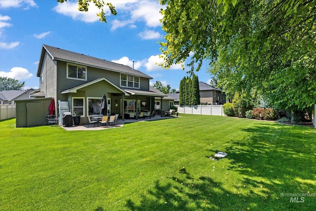 back of house with a patio area, a yard, and a storage unit