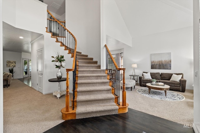 stairs with carpet floors and high vaulted ceiling