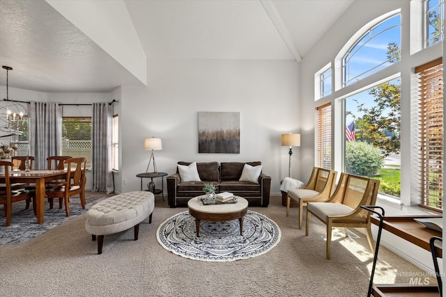 carpeted living room featuring plenty of natural light, high vaulted ceiling, and an inviting chandelier