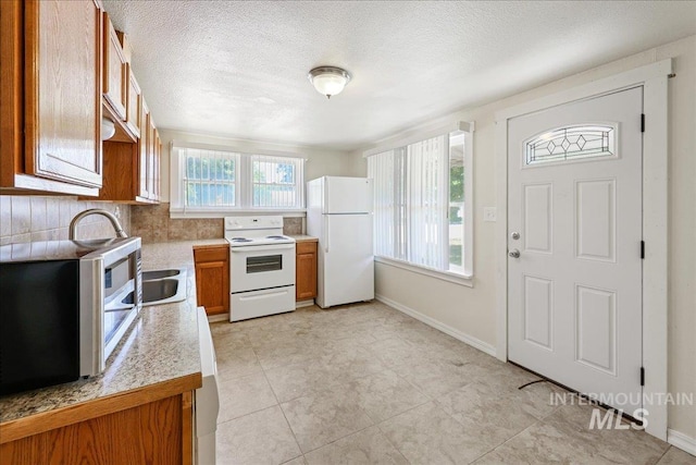 1324 E Oak St, Caldwell, ID 83605 - kitchen with white appliances, brown cabinetry, light countertops, decorative backsplash, and a textured ceiling