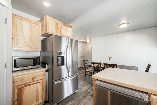 kitchen with dark hardwood / wood-style flooring, a textured ceiling, light brown cabinetry, and appliances with stainless steel finishes