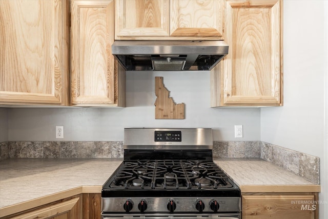 kitchen featuring range hood, light brown cabinets, and stainless steel gas range oven