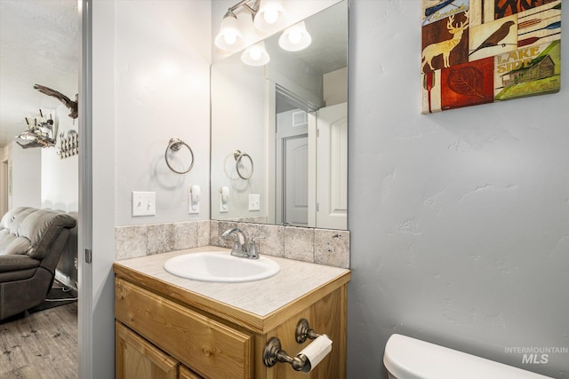 bathroom featuring toilet, hardwood / wood-style floors, and vanity