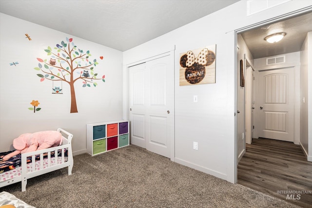 bedroom featuring a crib, a closet, and dark colored carpet