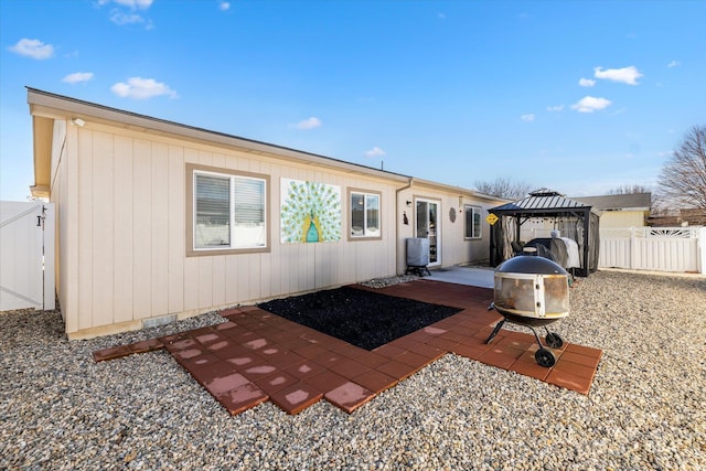 rear view of property with a gazebo, a fire pit, and a patio