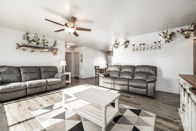 living room with ceiling fan and dark hardwood / wood-style flooring