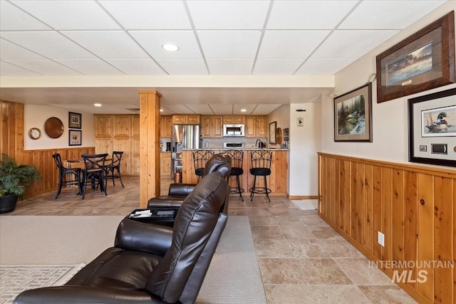 1640 S 5th W, Mountain Home, ID 83647 - living area with wood walls, a paneled ceiling, wainscoting, and baseboards