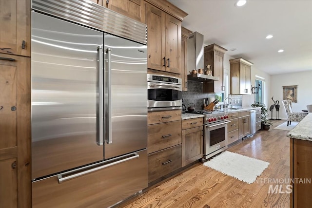 1640 S 5th W, Mountain Home, ID 83647 - kitchen featuring high end appliances, wall chimney exhaust hood, decorative backsplash, light wood-style floors, and recessed lighting