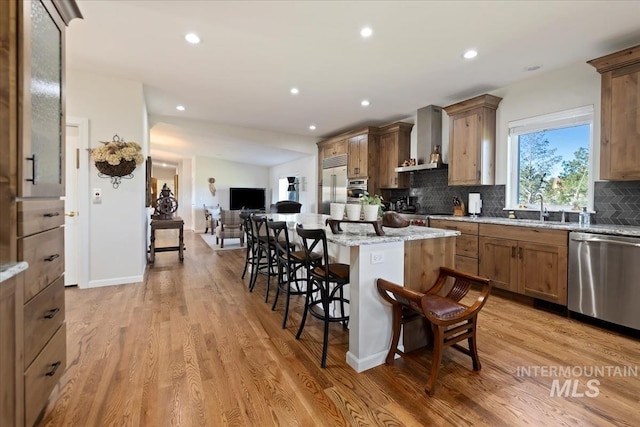 1640 S 5th W, Mountain Home, ID 83647 - kitchen with stainless steel appliances, wall chimney range hood, a breakfast bar, a sink, and decorative backsplash