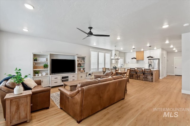 6811 W Los Flores Dr, Meridian, ID 83646 - living area with light wood-style floors, recessed lighting, baseboards, and ceiling fan with notable chandelier