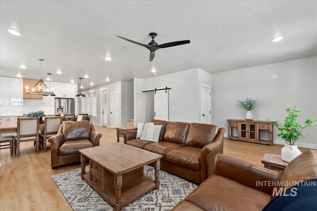 6811 W Los Flores Dr, Meridian, ID 83646 - living room featuring ceiling fan with notable chandelier, light wood-style flooring, recessed lighting, and a barn door