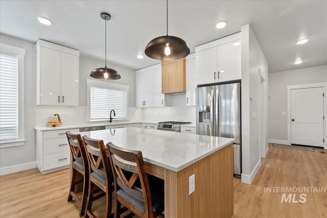 6811 W Los Flores Dr, Meridian, ID 83646 - kitchen featuring stainless steel appliances, a kitchen island, white cabinetry, and pendant lighting