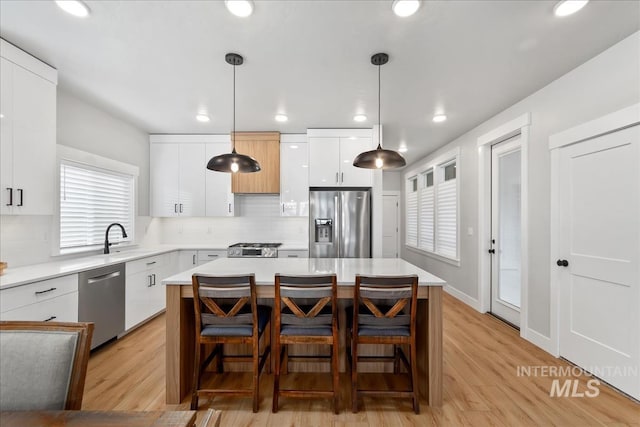 6811 W Los Flores Dr, Meridian, ID 83646 - kitchen with stainless steel appliances, hanging light fixtures, a kitchen island, and light countertops