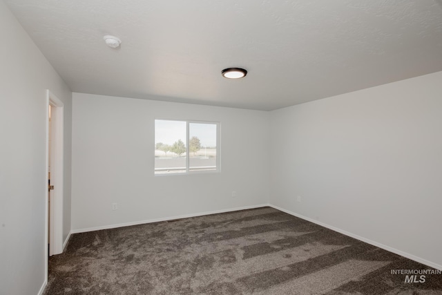 unfurnished room with dark colored carpet