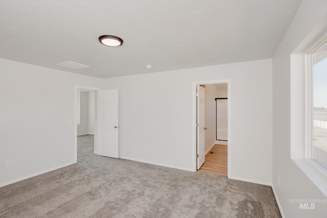 carpeted empty room with a textured ceiling