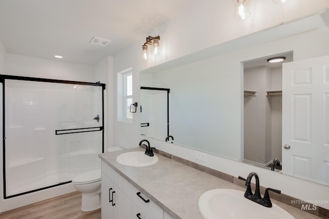 bathroom with hardwood / wood-style flooring, vanity, toilet, and a shower with door