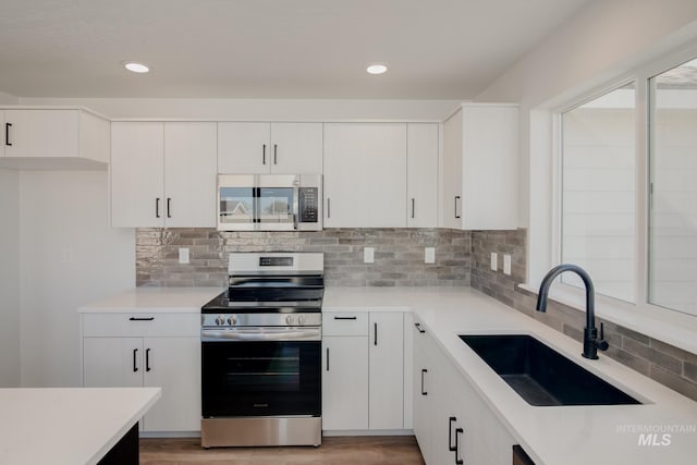 kitchen featuring white cabinets, sink, stainless steel appliances, and light hardwood / wood-style flooring