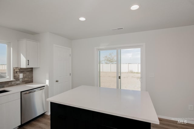 kitchen featuring tasteful backsplash, dark wood-type flooring, dishwasher, a center island, and white cabinetry