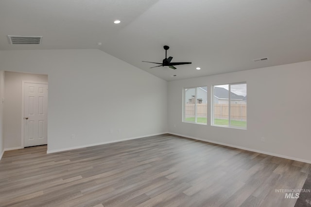 empty room featuring vaulted ceiling, light wood-type flooring, and visible vents