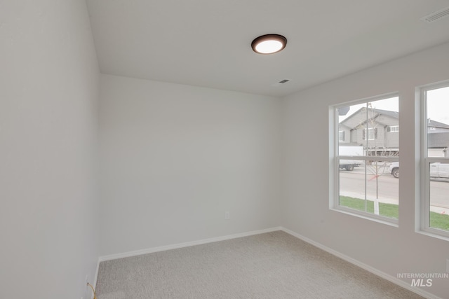 spare room with carpet, visible vents, and baseboards