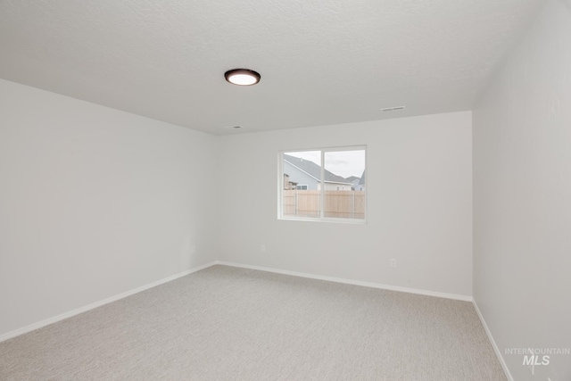 empty room featuring carpet floors, a textured ceiling, and baseboards