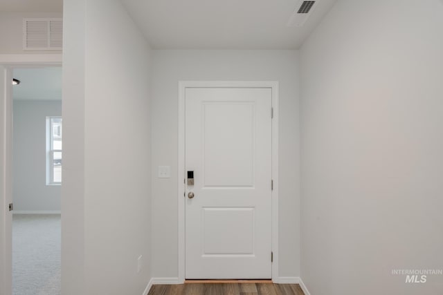 doorway to outside featuring baseboards, visible vents, and wood finished floors