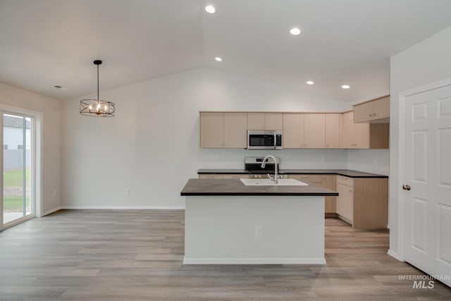 kitchen featuring stainless steel microwave, dark countertops, a sink, and decorative light fixtures