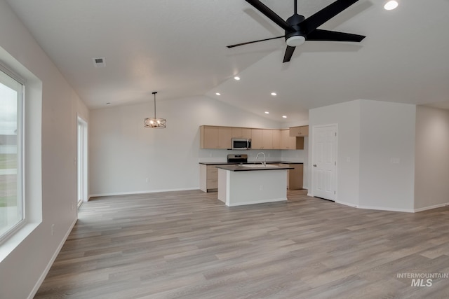 kitchen with stainless steel appliances, dark countertops, open floor plan, and decorative light fixtures